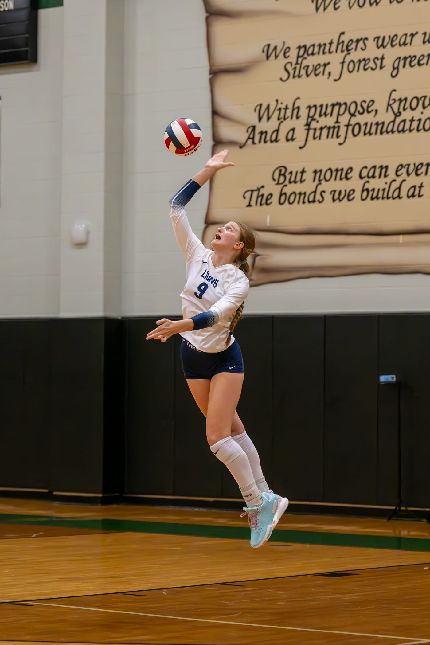 A high school volleyball player mid-serve